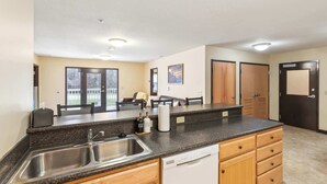 A kitchen with granite countertops, stainless steel sink, wooden cabinets, and a dishwasher. - Modern Retreat Near Campus & Local Trails (Mansfield)