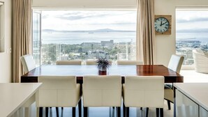 A dining area with a view of the city and sea, a wooden table, and four chairs. - Spacious 3Bed Apt Overlooking Cape Town Panova (Cape Town)