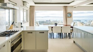 A modern kitchen with a central island, built-in oven, and a view of the city and sea. - Spacious 3Bed Apt Overlooking Cape Town Panova (Cape Town)