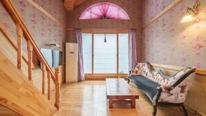 A cozy living room with a wooden staircase, a sofa, a coffee table, and a large window with curtains. - Gyeongju Silla Palace Pension (Gyeongju)