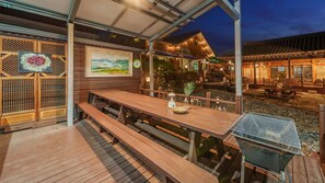 An outdoor wooden deck with benches and a grill, surrounded by wooden fences and traditional Japanese decor. - Gyeongju Silla Palace Pension (Gyeongju)
