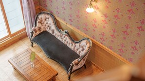 A room with a vintage sofa, a wooden table with a vase, and patterned wallpaper. - Gyeongju Silla Palace Pension (Gyeongju)