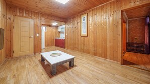 A wooden interior with a dining table, a kitchen area, and a traditional Japanese calligraphy piece on the wall. - Gyeongju Silla Palace Pension (Gyeongju)