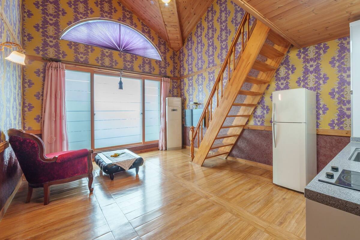 Ein Holzinnenraum mit Treppe, Kühlschrank, Spüle und einem Sessel.