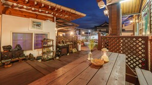 Eine Terrasse aus Holz mit einem Laternenlicht, einem Holztisch und einem dekorativen Regal mit Steinen.