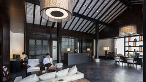 Un hall espacioso con una recepción, zona de estar y un amplio ventanal que proporciona luz natural.