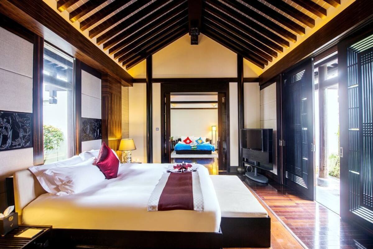 Ein Hotelzimmer mit einem großen Bett, einem Fernseher und Blick ins Freie.