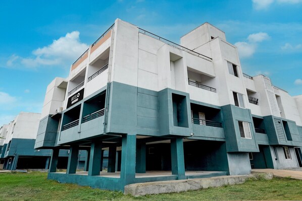 A modern hotel with a flat roof, multiple balconies, and a sign indicating it is a hotel.