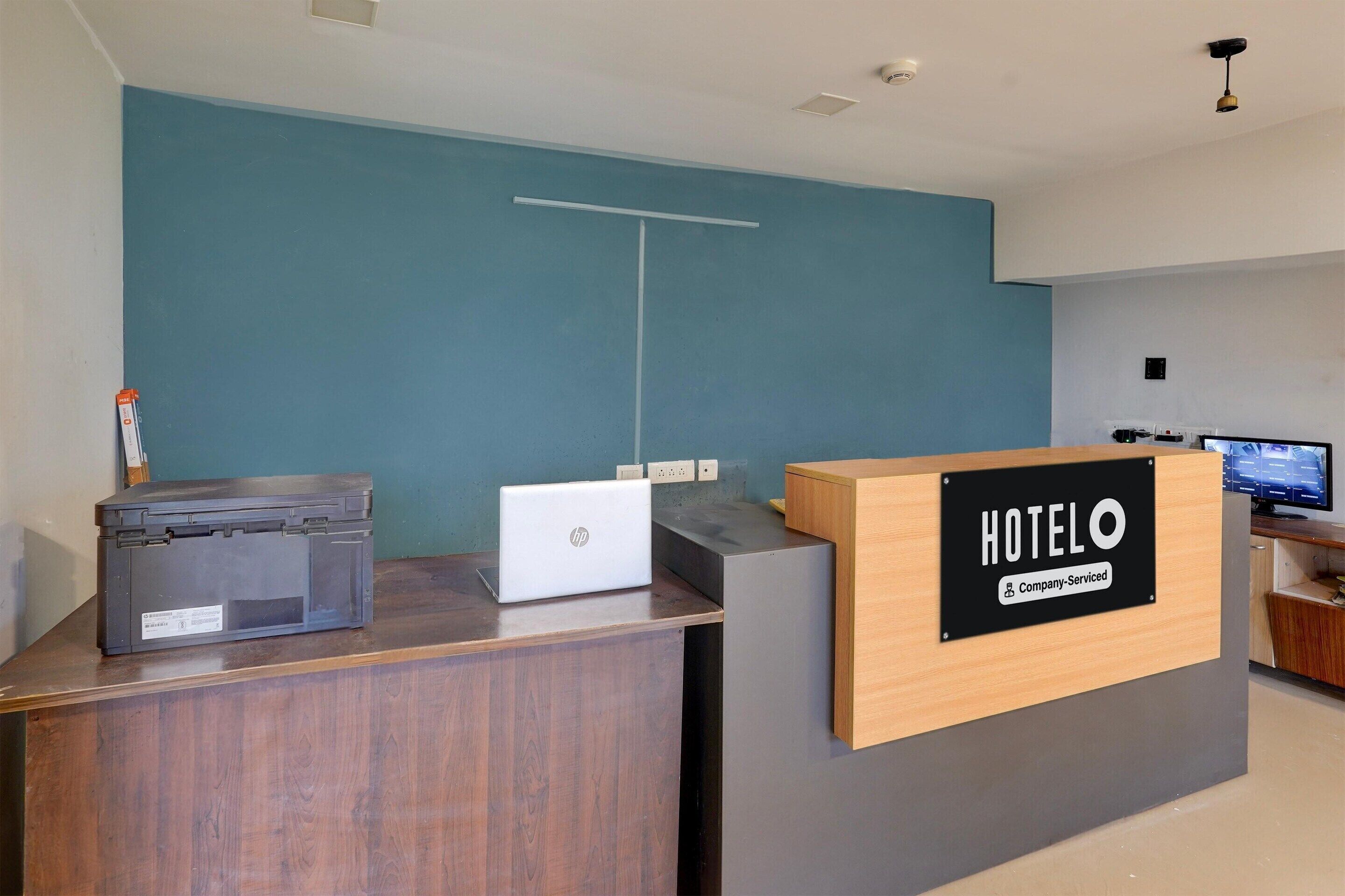Un mostrador de recepción con un cartel que dice "HOTELO" y una computadora portátil.