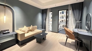 A modern living room with a sofa, coffee table, and a dining area with a chair and table. - GARDEN PHOENIX HOTEL (Vu Ninh)