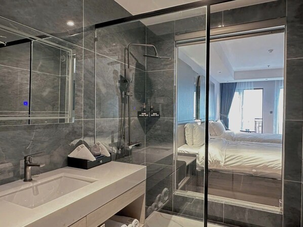 Un baño moderno con cabina de ducha de vidrio, un espejo grande y un lavabo con dispensador de toallas.