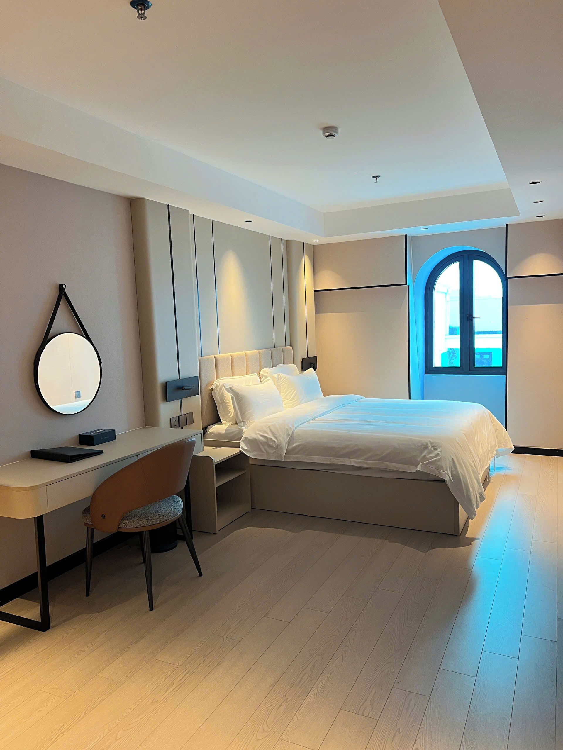 Une chambre moderne avec un lit, un bureau, une chaise et une grande fenêtre.