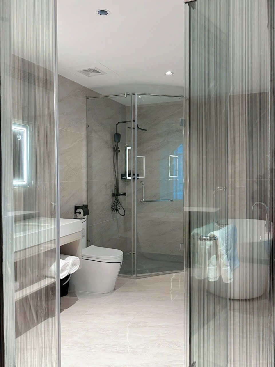 A modern bathroom with a glass-enclosed shower, a toilet, and a sink.