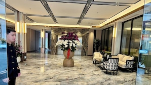 A lobby with a marble floor, a large floral arrangement, and seating areas. - GARDEN PHOENIX HOTEL (Vu Ninh)