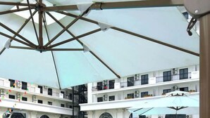 A swimming pool with lounge chairs and umbrellas, surrounded by a multi-story building with balconies. - GARDEN PHOENIX HOTEL (Vu Ninh)