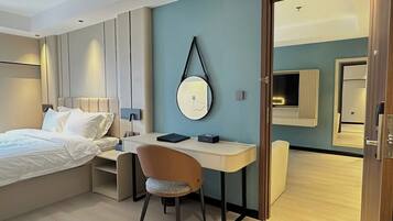 A modern hotel room with a bed, desk, chair, and a large mirror.