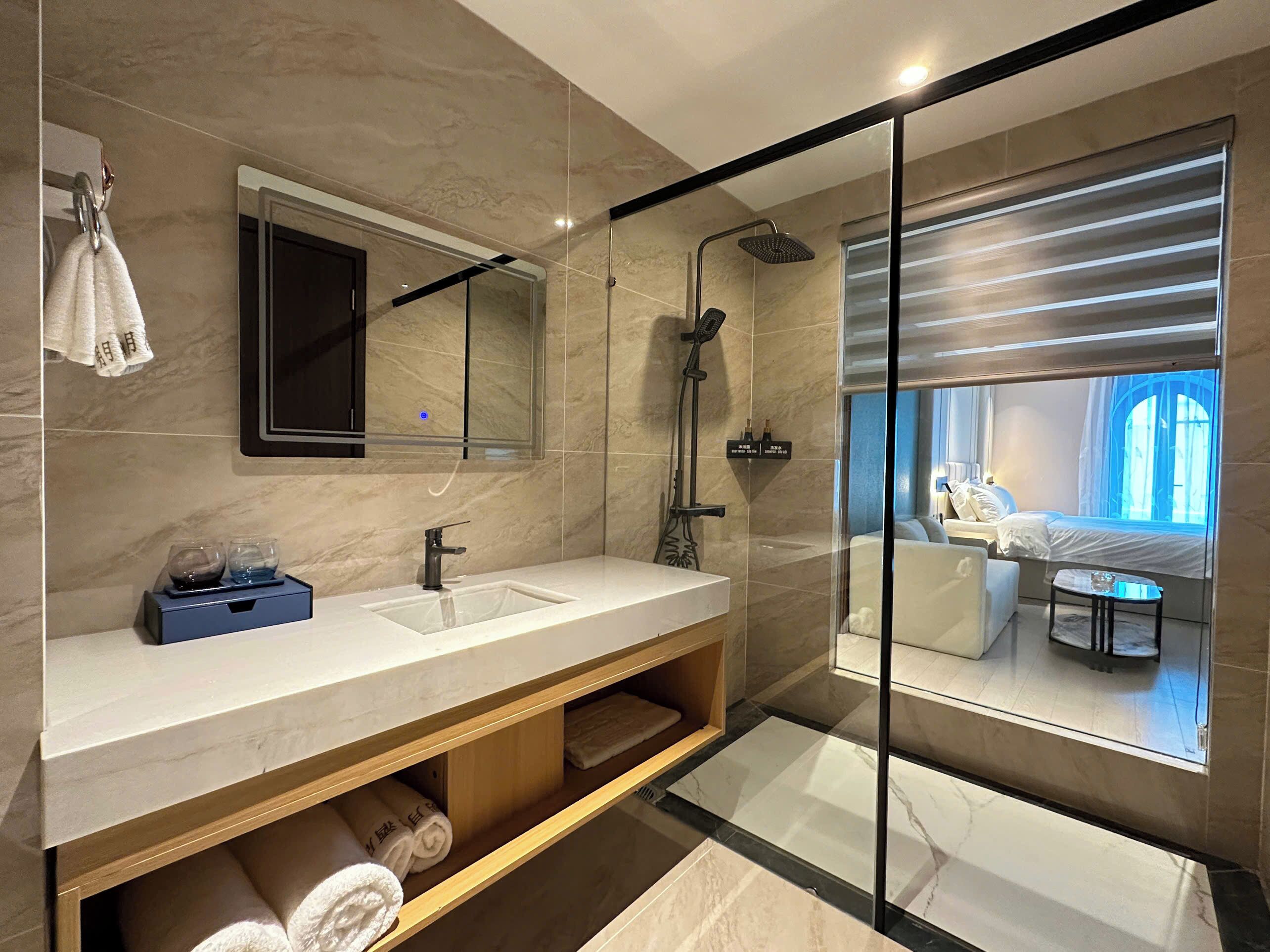Un baño moderno con un espejo grande, dos lavamanos, una ducha y cabina de ducha con paredes de vidrio.