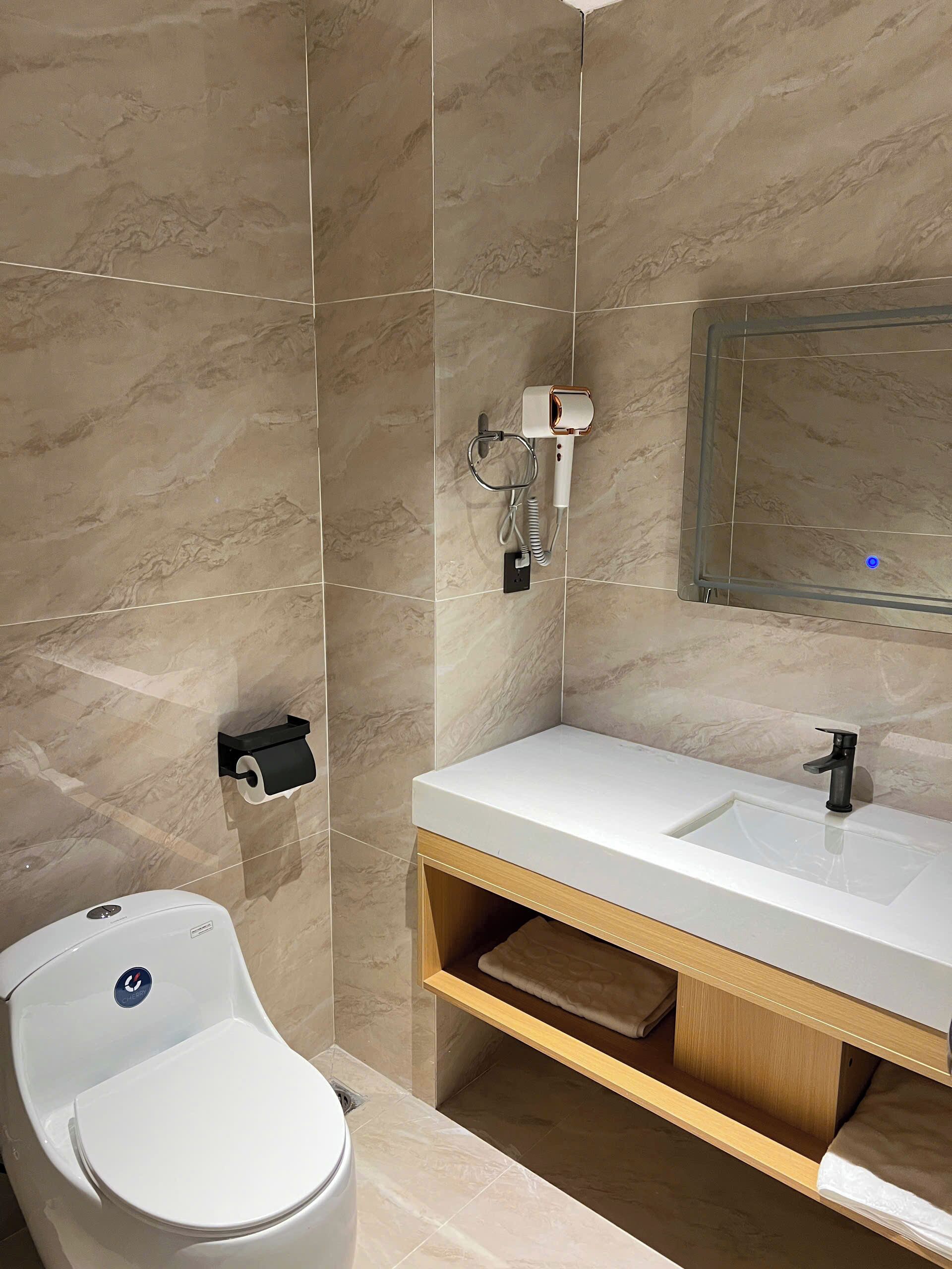 A modern bathroom with a white sink, a mirror, a toilet, and a towel rack.
