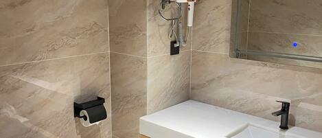 A modern bathroom with a white sink, a mirror, a toilet, and a towel rack.