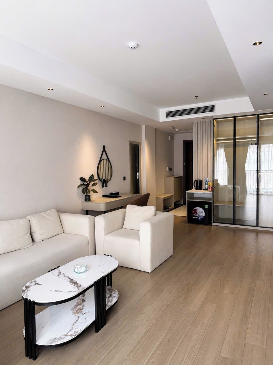 Una sala de estar moderna con un sofá, una mesa de centro y un separador de vidrio.