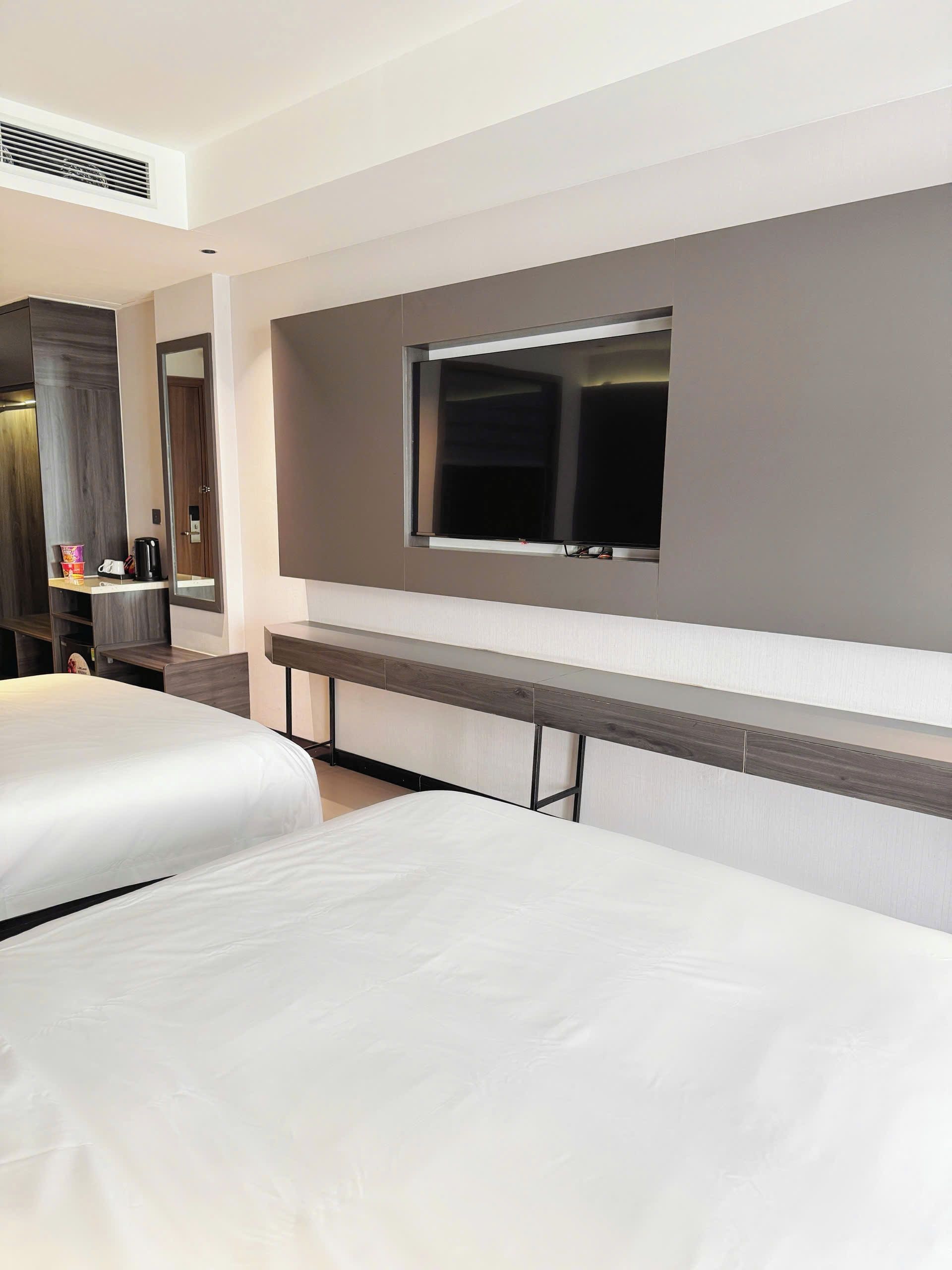 Une chambre d’hôtel avec un lit, un téléviseur fixé au mur et un miroir.