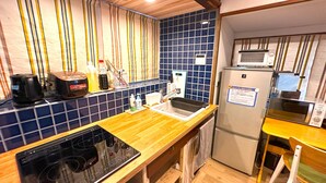 Una cocina compacta con encimera de madera, estufa integrada, microondas y refrigerador.