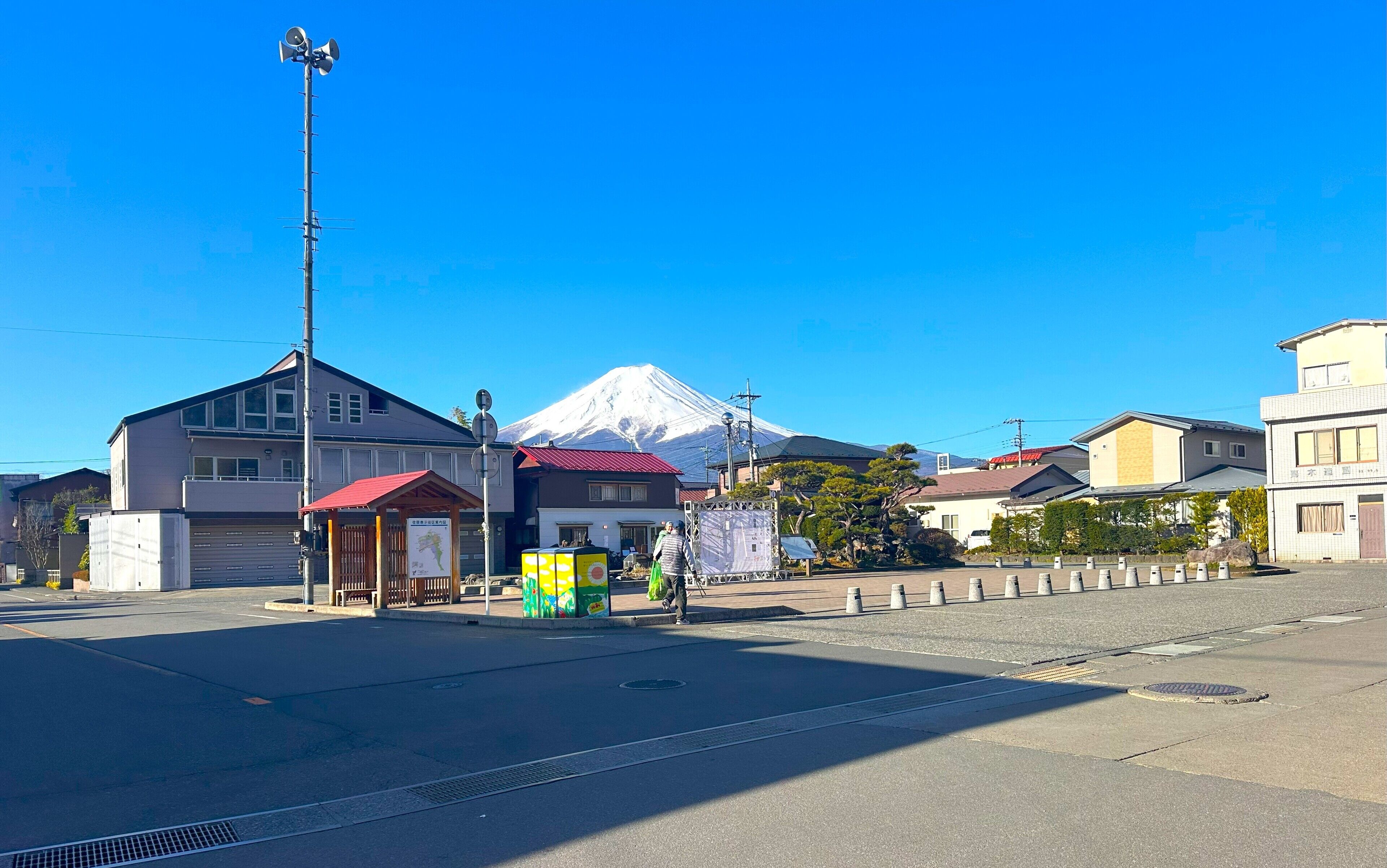 A street with buildings, a red-roofed structure, and a mountain in the background.