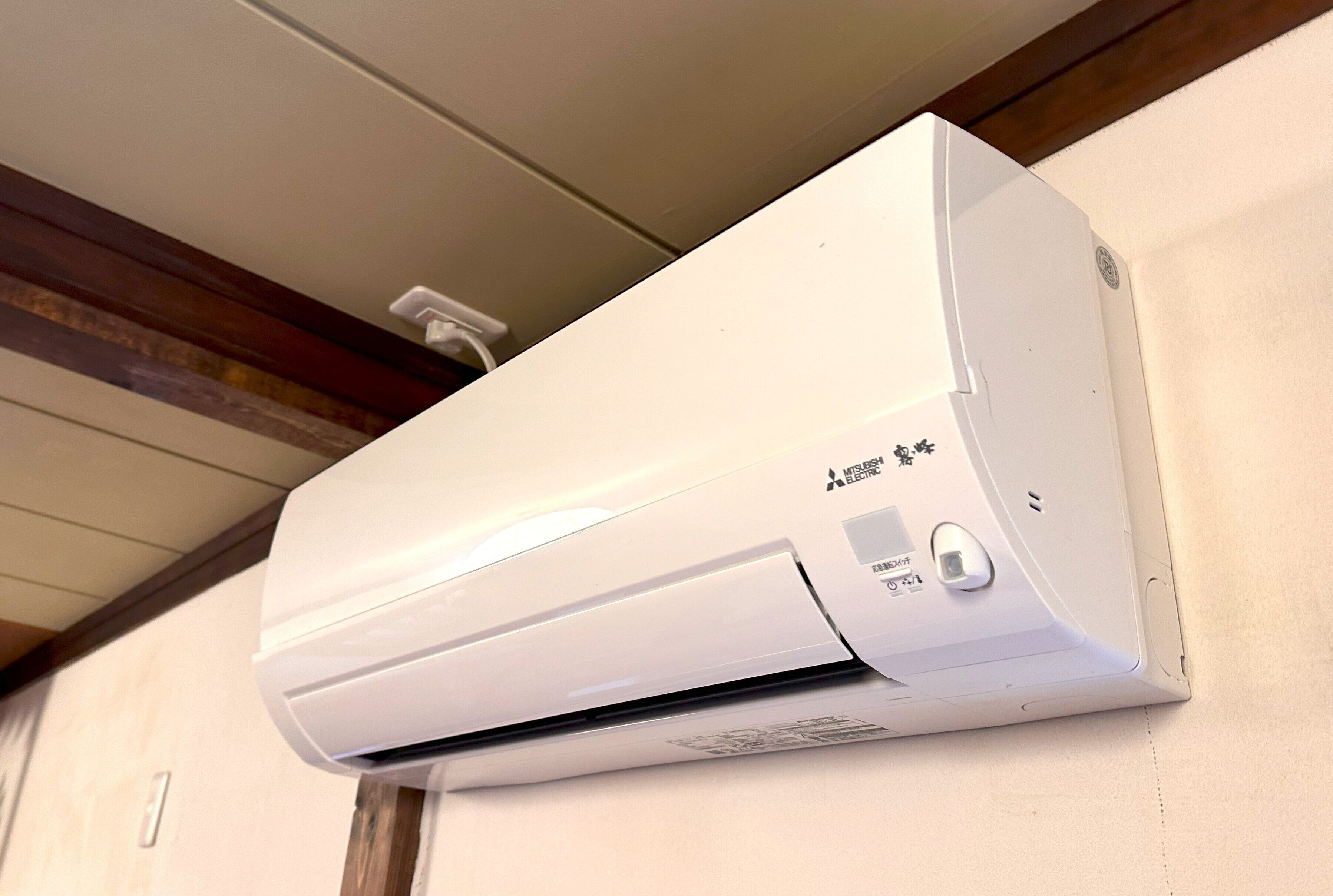A wall-mounted air conditioning unit with a control panel and a power outlet.