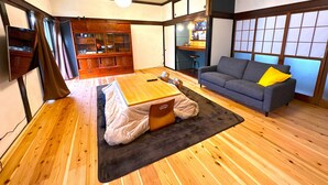 Una habitación tradicional japonesa con suelo de tatami, una mesa baja, un sofá y un mueble con puertas de cristal.