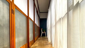 Un pasillo con suelo de madera y ventanas amplias con paneles de vidrio esmerilado.
