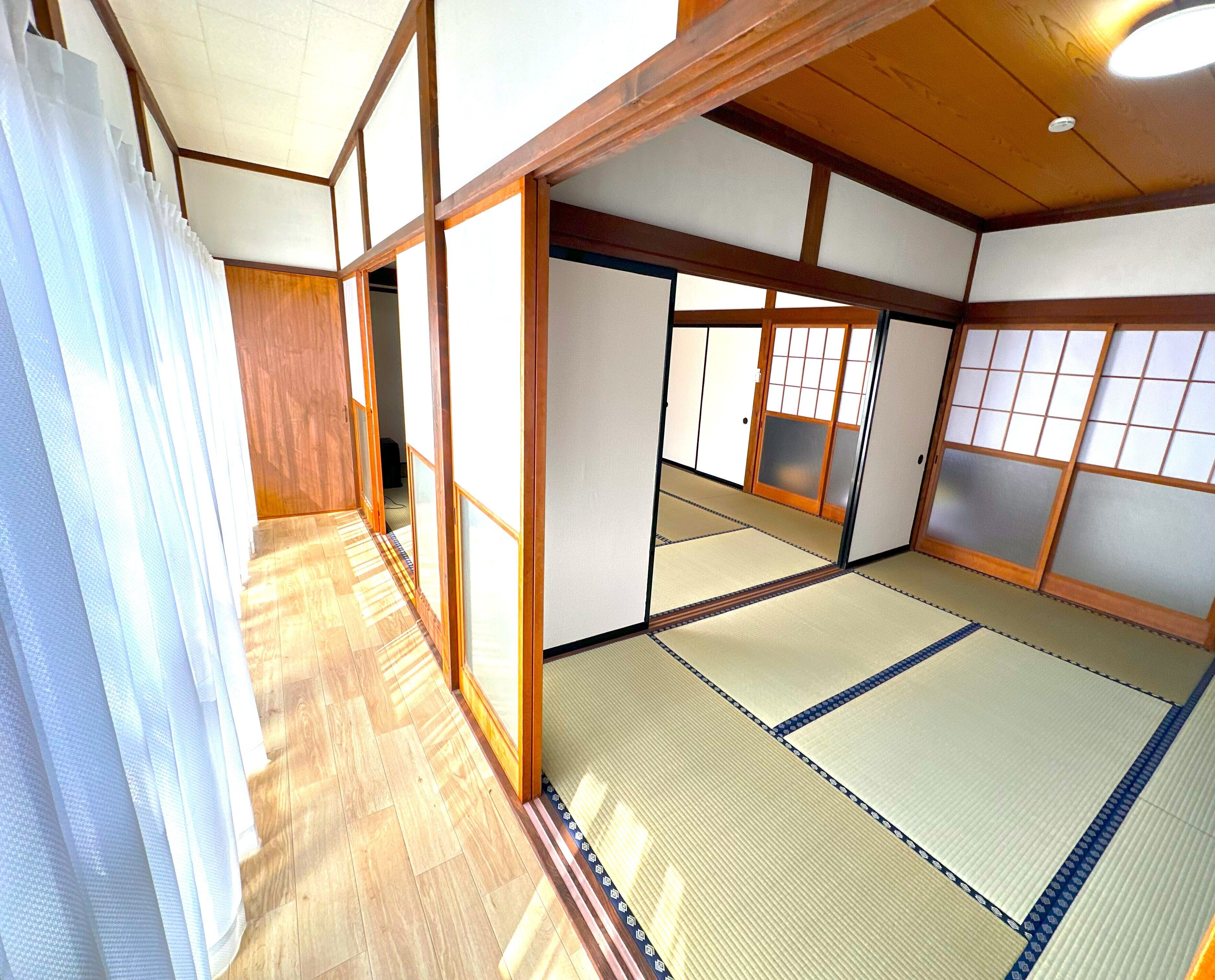 Una habitación japonesa tradicional con suelo de tatami, puertas correderas y vigas de madera.