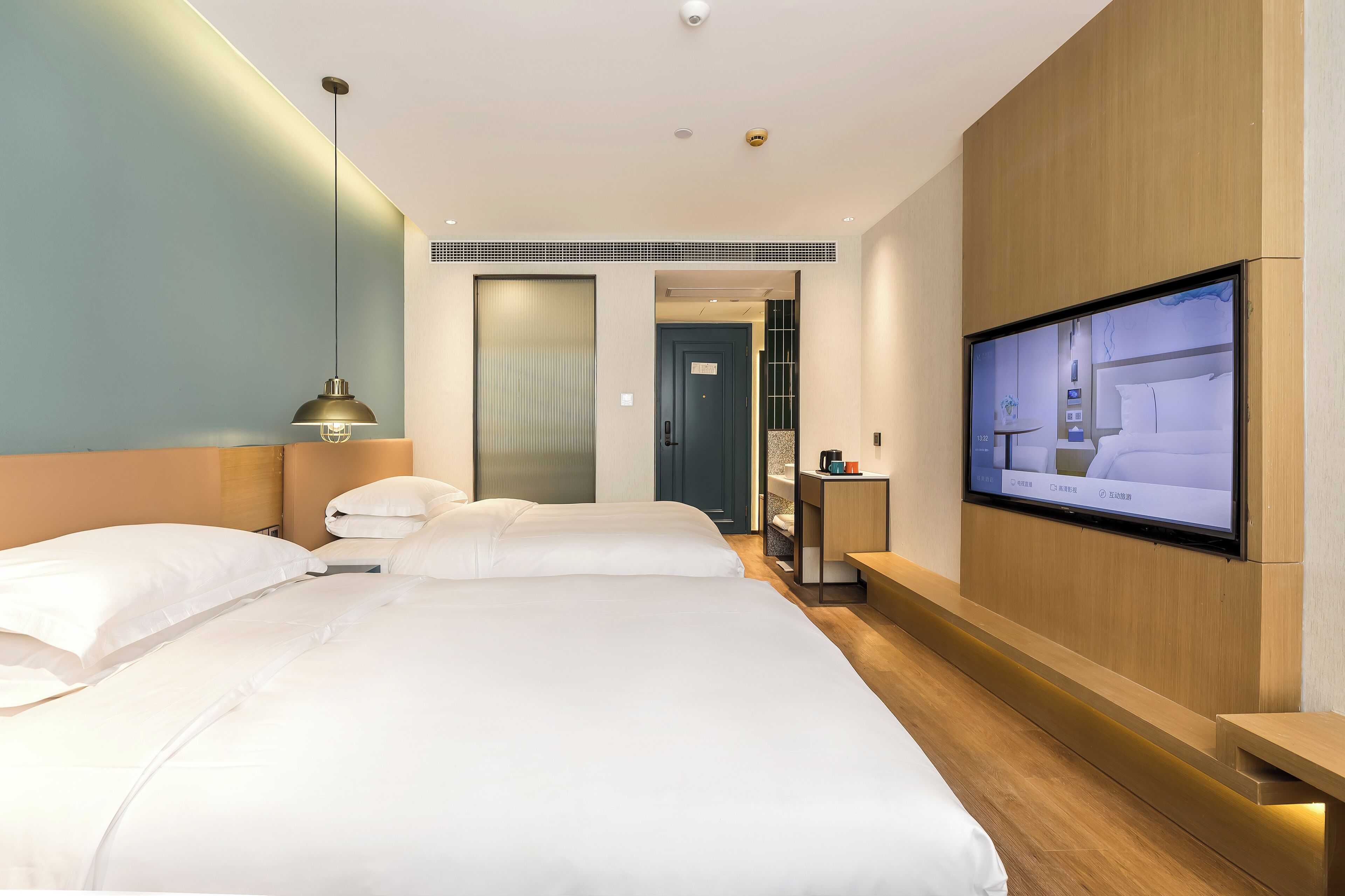 Una camera d'albergo con un letto grande, una TV a parete e una testiera in legno.