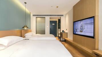 Una camera d'albergo con un letto grande, una TV a parete e una testiera in legno.