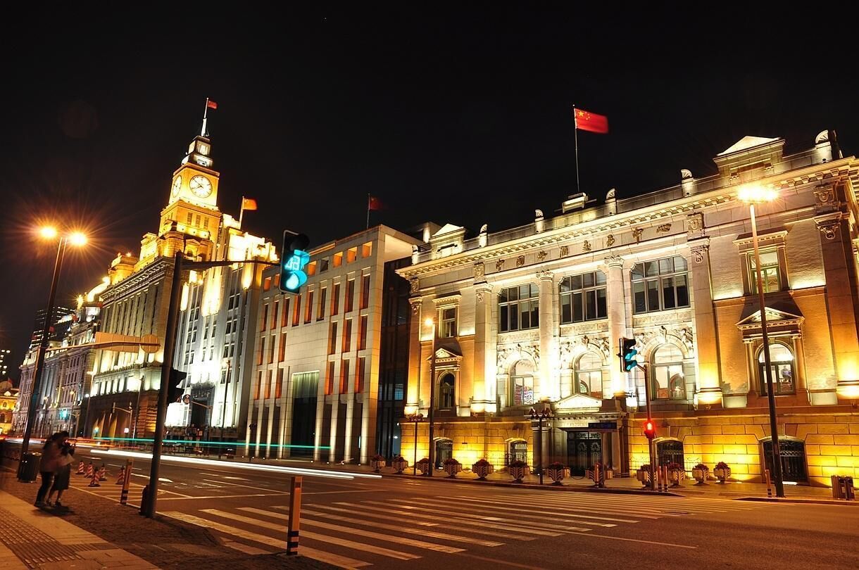 A historic building with classical architecture, featuring a prominent clock tower and flags.