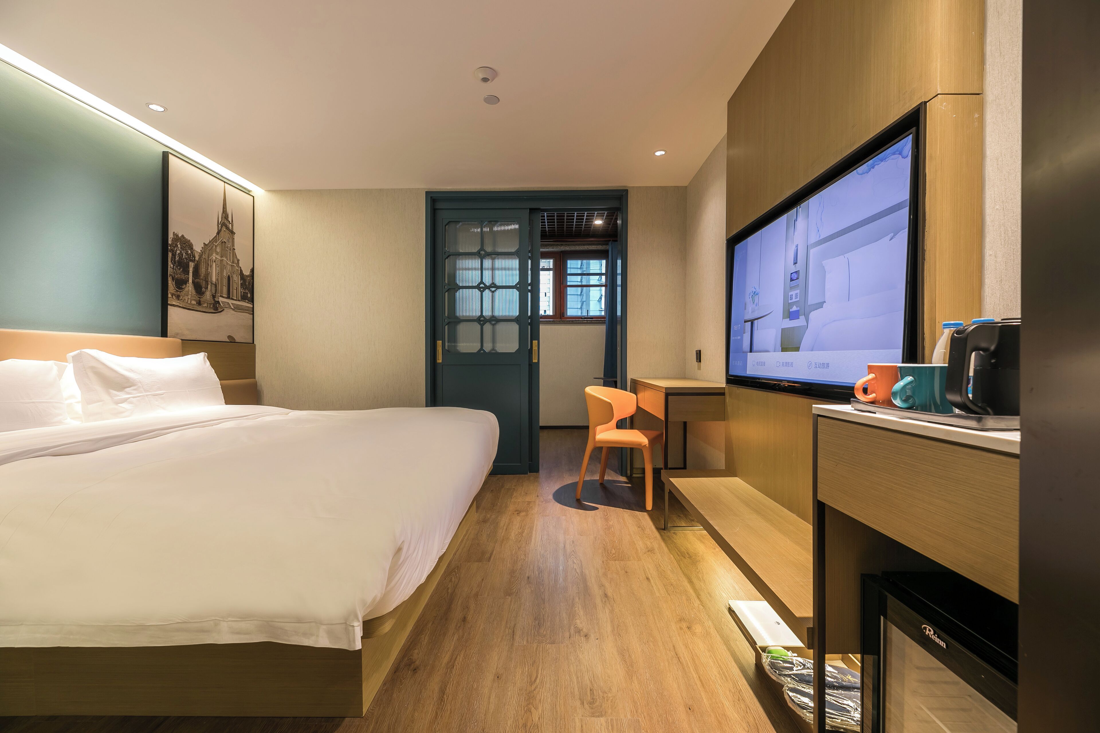 Une chambre d’hôtel équipée d’un lit, d’un bureau, d’une chaise, d’une télévision et d’un réfrigérateur.