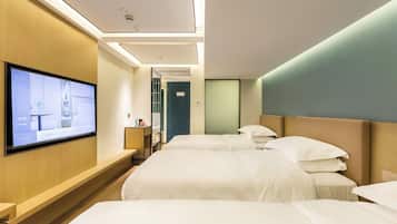 A hotel room with two beds, a TV mounted on the wall, and a wooden bench.