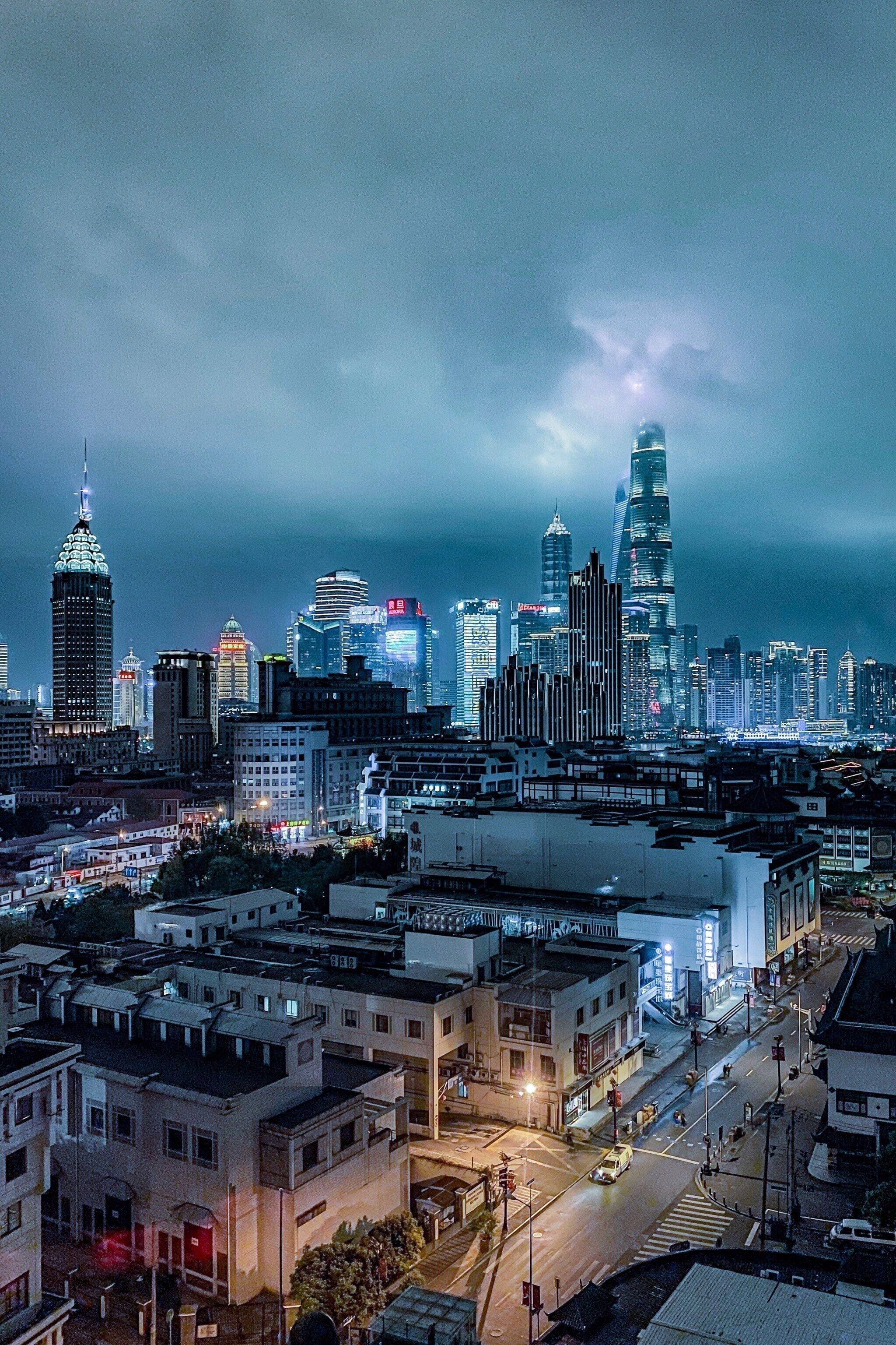 Une vue nocturne d’une ville, avec des gratte-ciel modernes et un mélange de bâtiments plus anciens.