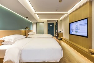 A hotel room with two beds, a TV on the wall, and a wooden reception desk.