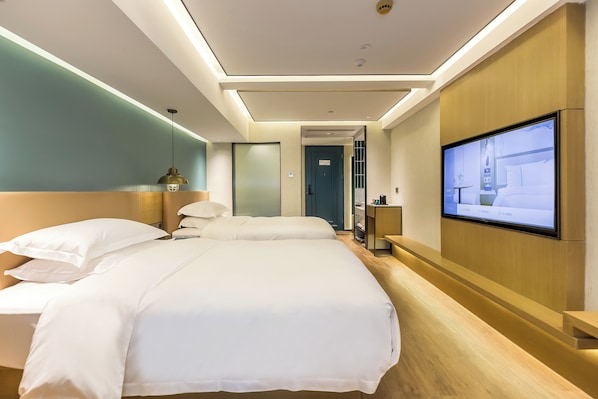 Una habitación de hotel con dos camas, un televisor en la pared y un mostrador de recepción de madera.