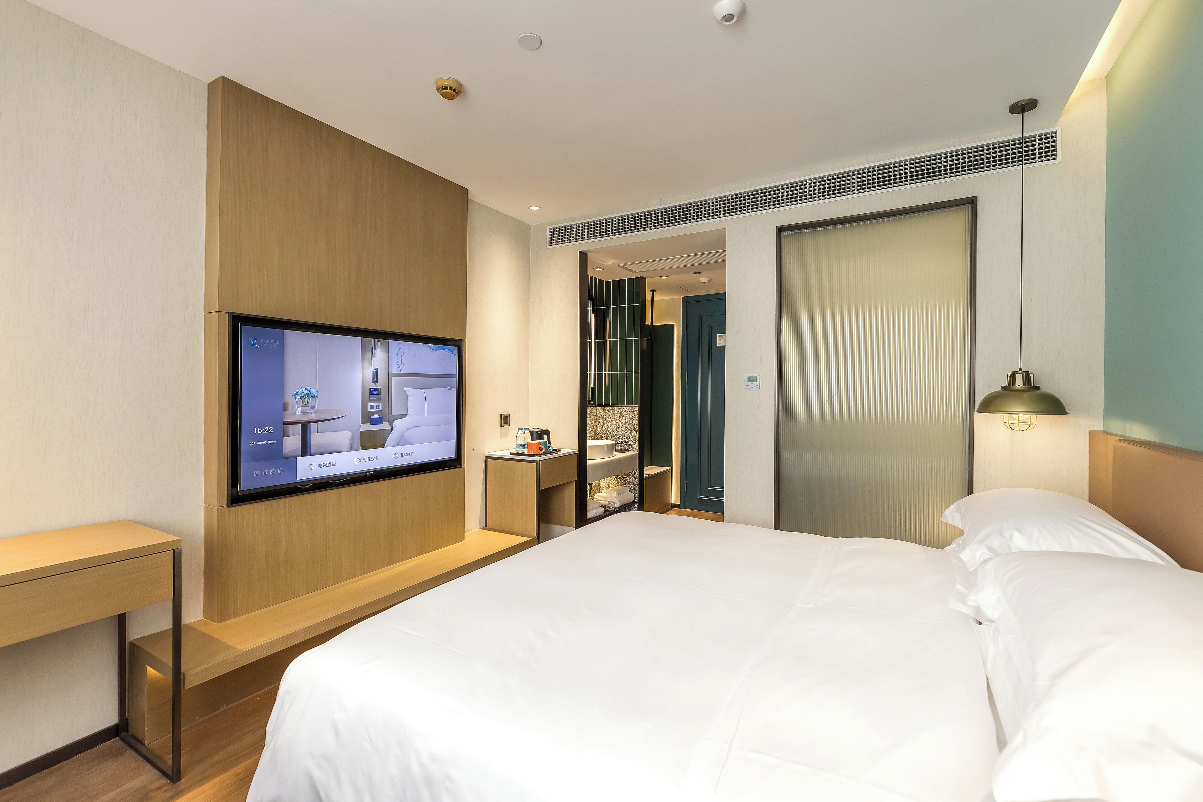 Ett hotellrum med en säng, en tv som är monterad på väggen, ett skrivbord och ett badrum som syns genom en öppen dörr.