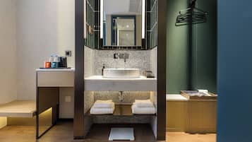 A modern bathroom with a freestanding sink, a mirror, and a towel rack.