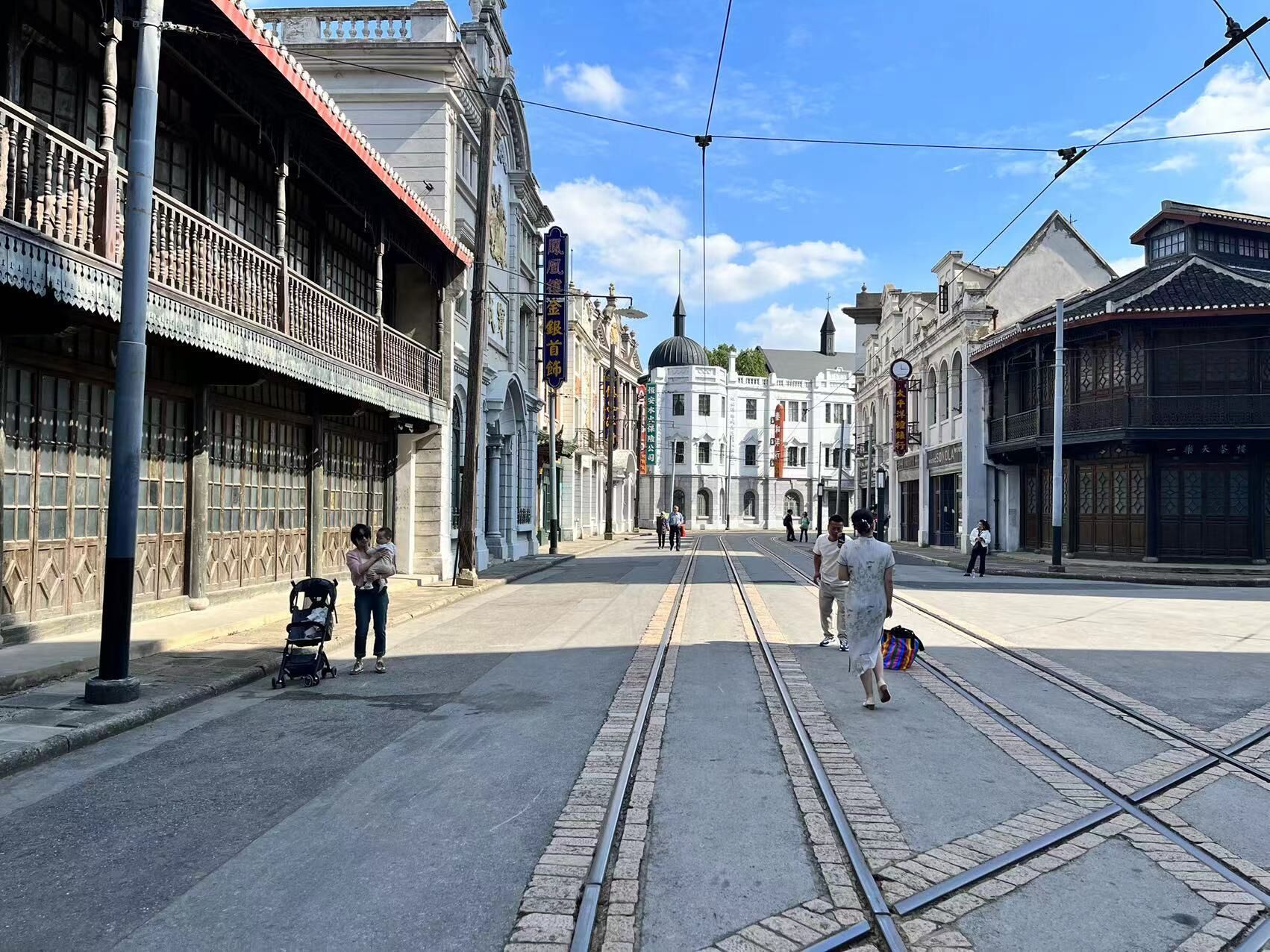 A street with tram tracks, historic buildings, and a clear sky.