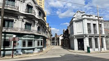 Une rue bordée de bâtiments historiques, dont un bâtiment doté d’une horloge et un autre orné d’un balcon.