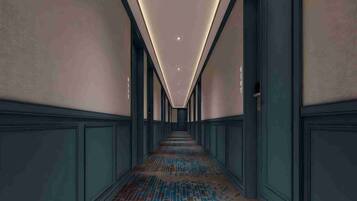 A long, narrow hallway with patterned flooring and large windows on both sides.