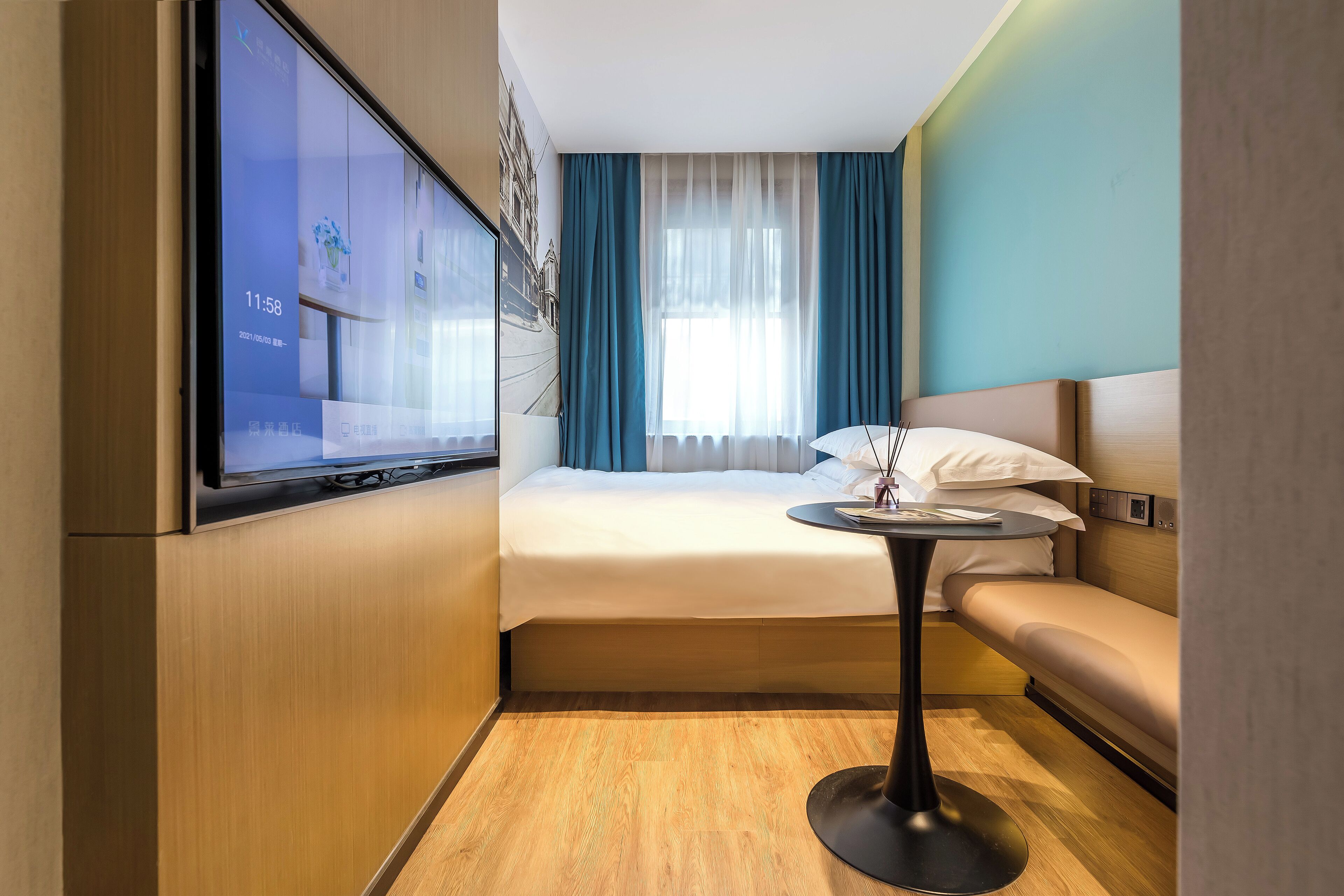Una habitación de hotel pequeña con una cama, una mesita, un sofá y un televisor montado en la pared.