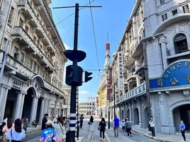 Escena callejera con edificios históricos, un tranvía y peatones.