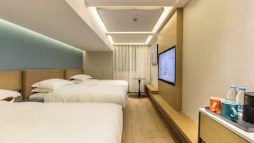 A hotel room with two beds, a small table with a TV, and a coffee maker on the side table.