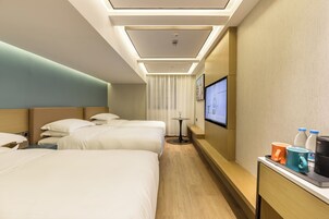 A hotel room with two beds, a small table with a TV, and a coffee maker on the side table.