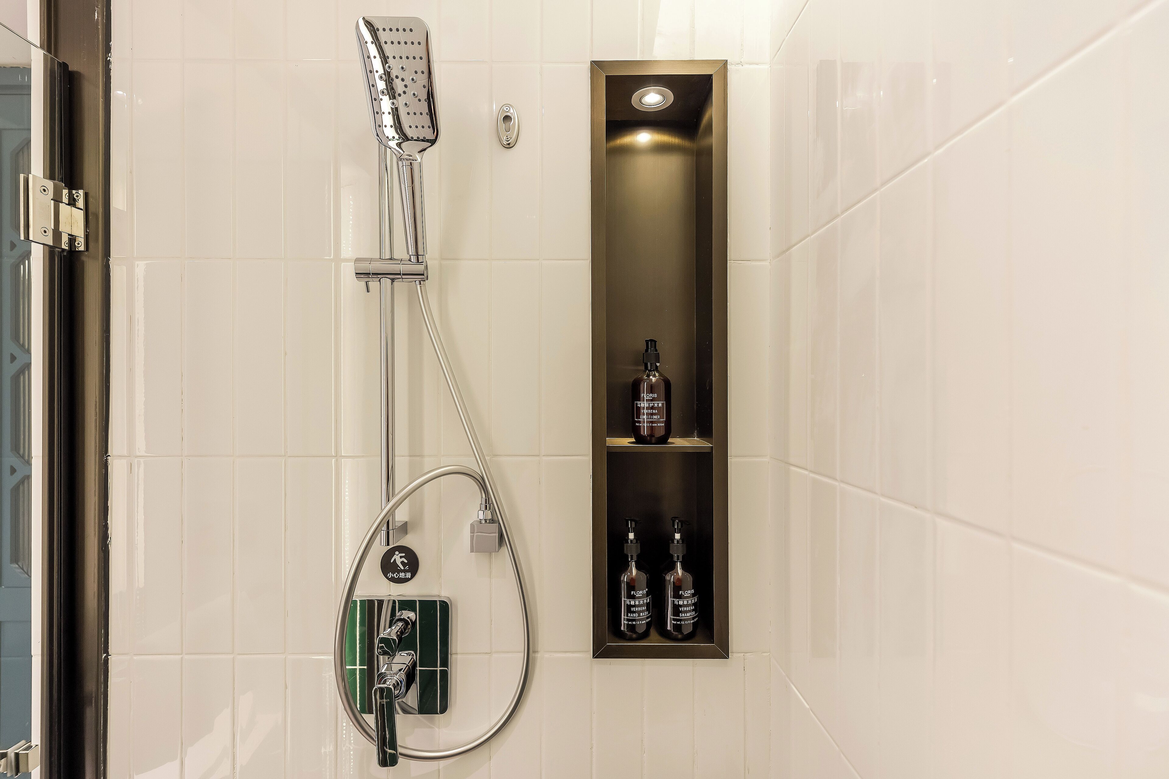 A bathroom with a shower, a toilet, and a shelf with toiletries.