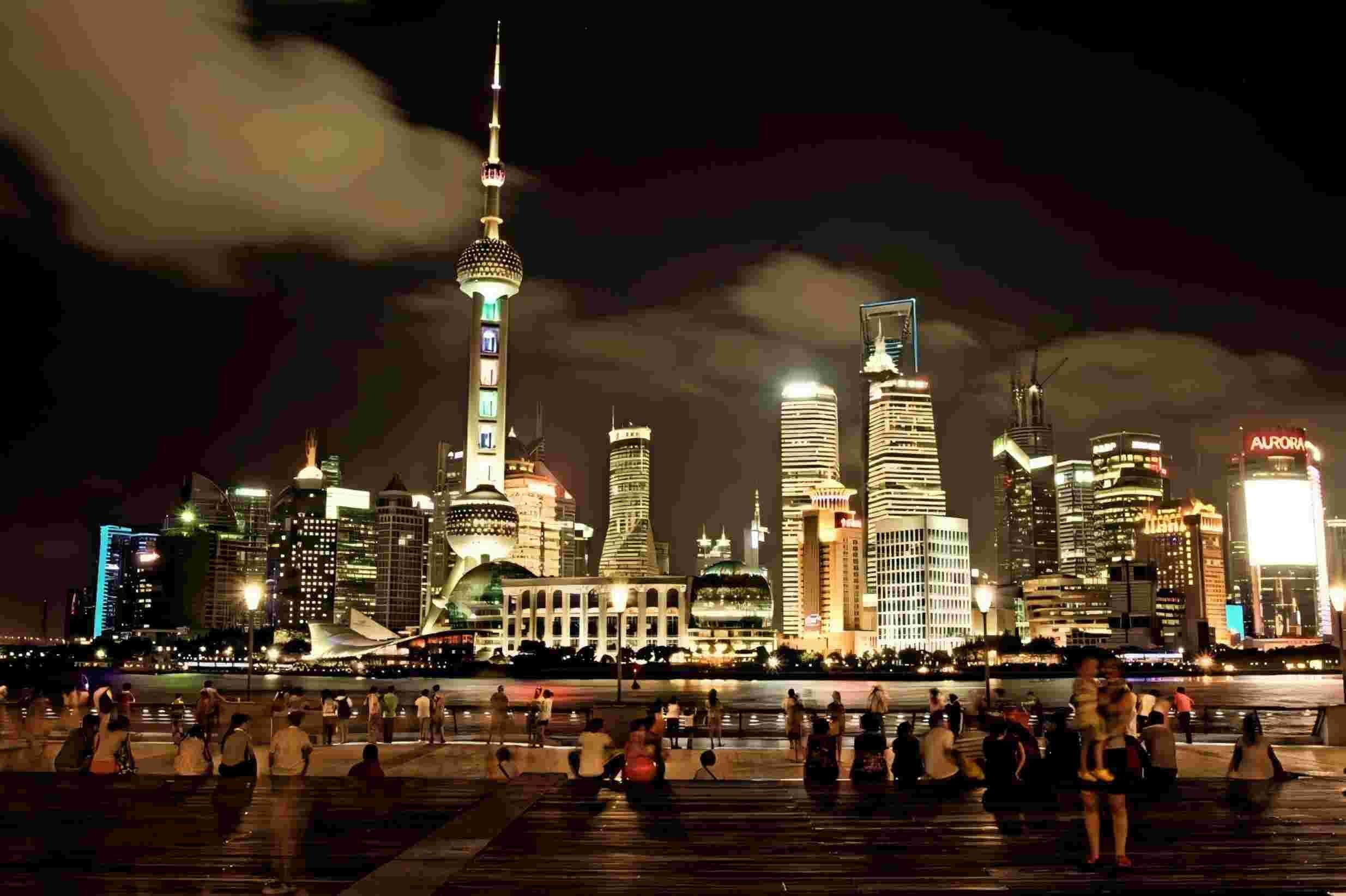 Eine nächtliche Skyline mit beleuchteten Wolkenkratzern und einem markanten Turm.